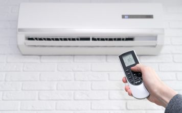 All About Comfort Cooling And Heatinghome air conditioner and hand with remote control